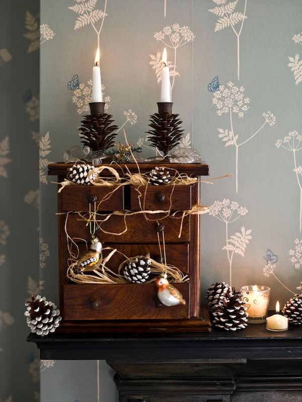 Scene with paint-dipped pinecones and bird ornaments that seem to be nesting in drawers.