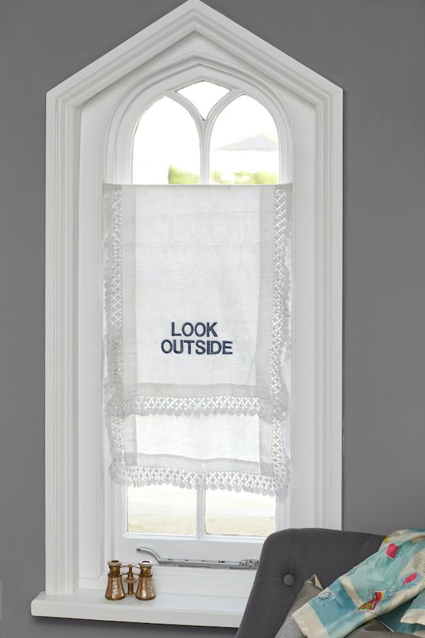 Vintage lace runner used as window covering with embroidery.