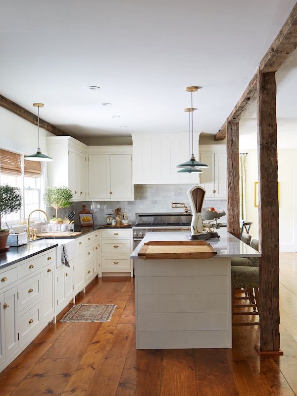 Kitchen with French pastry board, white cabinets, brass handles and wood beams.